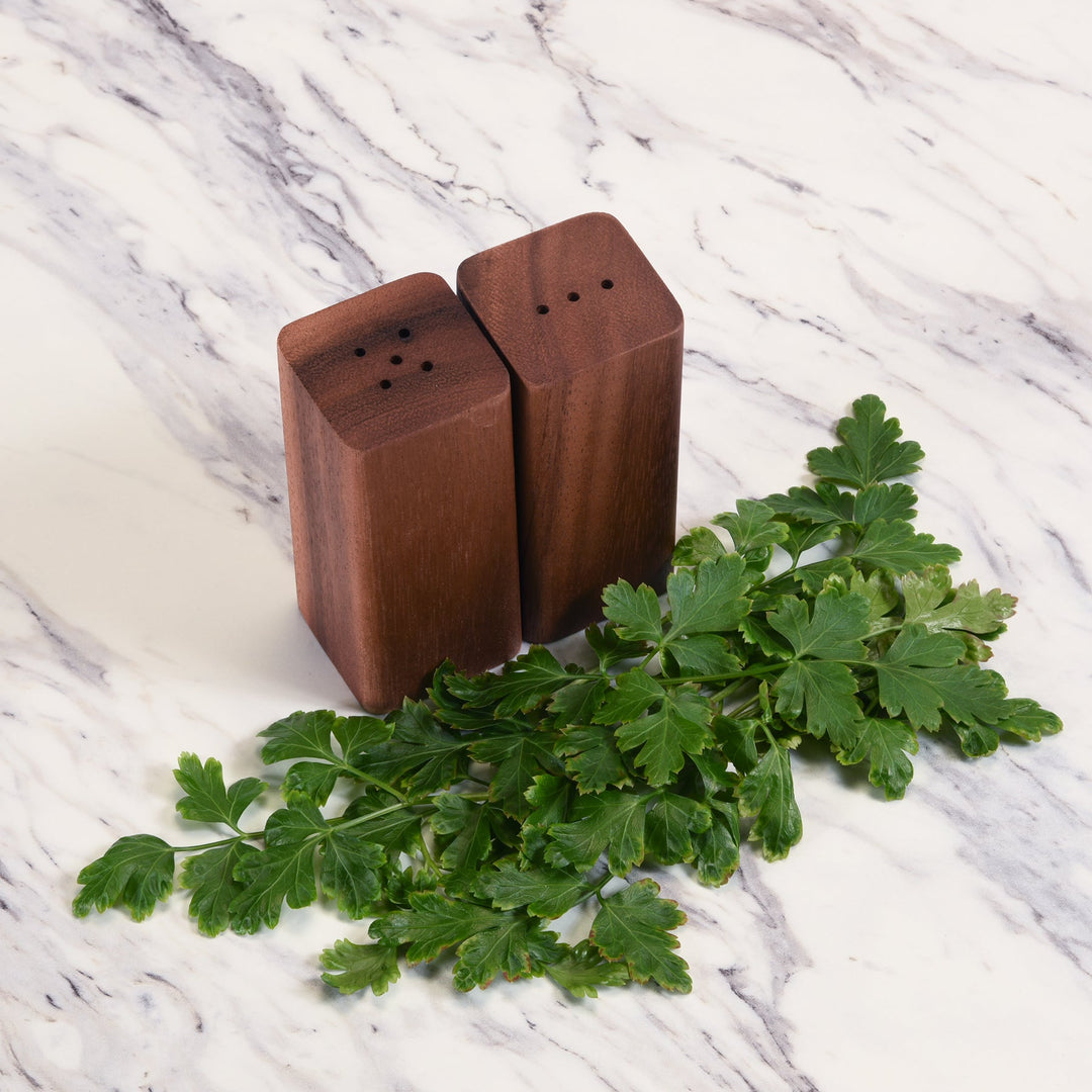 Acacia wood salt and pepper shakers with a matching base in natural wood.