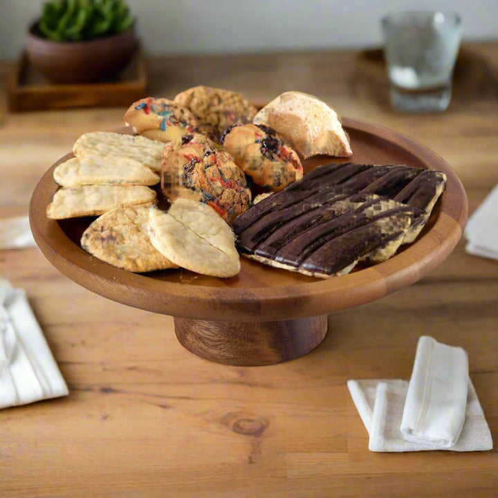 Large acacia wood cake stand with a natural finish for displaying baked goods.
