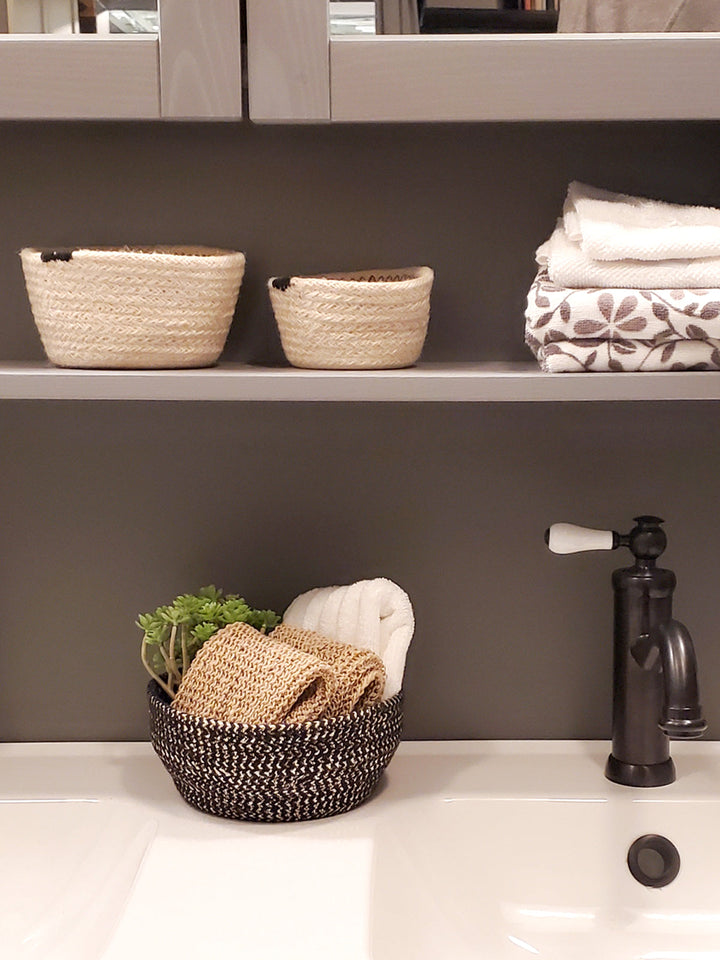 Pair of black braided jute storage bowls with shimmering golden yarn detail