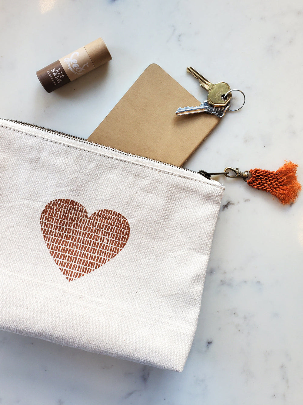 Cream canvas pouch with cinnamon-colored love print and hemp tassel pull