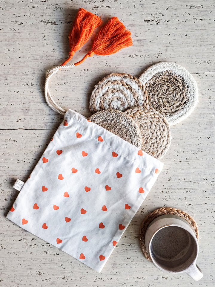 Handwoven natural fiber coasters packaged in a hand-printed heart pouch