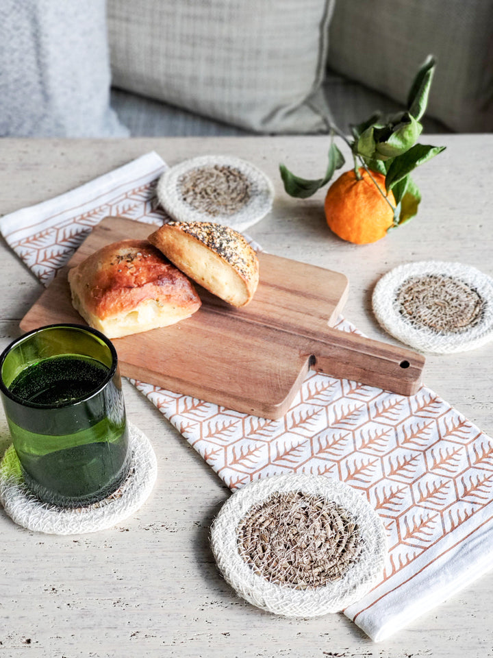 Two-tone seagrass coasters featuring tan center and contrasting cream edge band