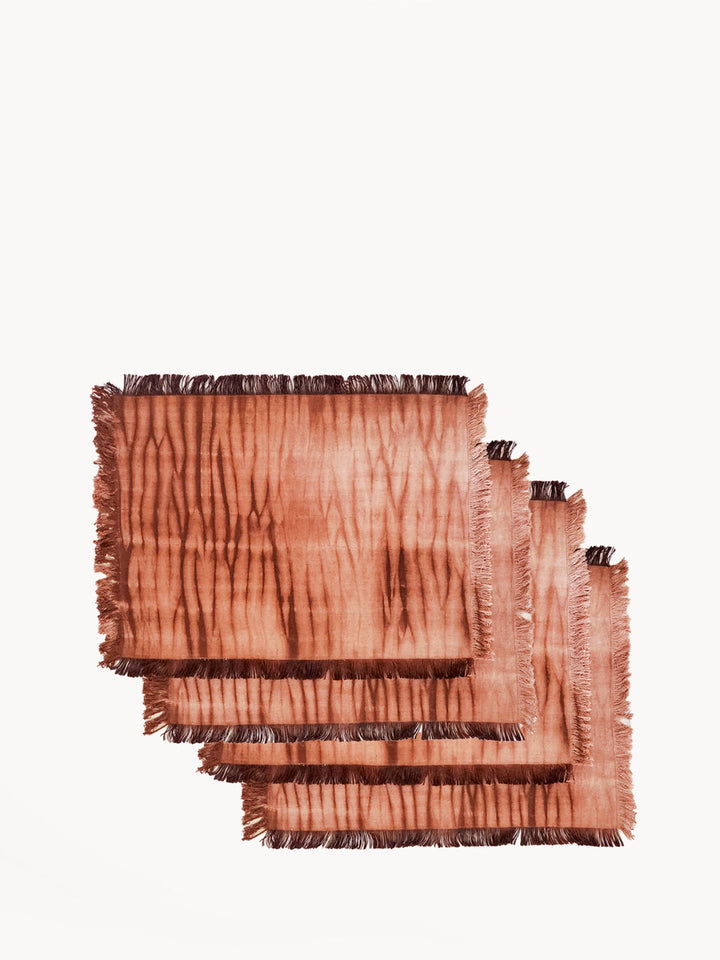 Shibori-dyed cotton placemats in warm rust with linear pattern and fringed edges, set of 4