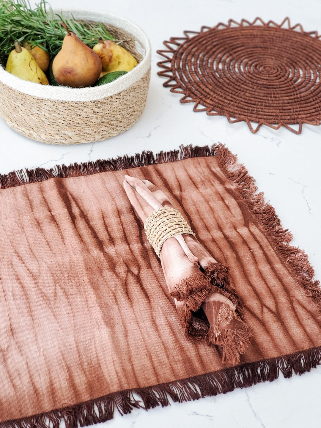 Hand-dyed shibori cotton placemats in warm earth tones with fringed edges
