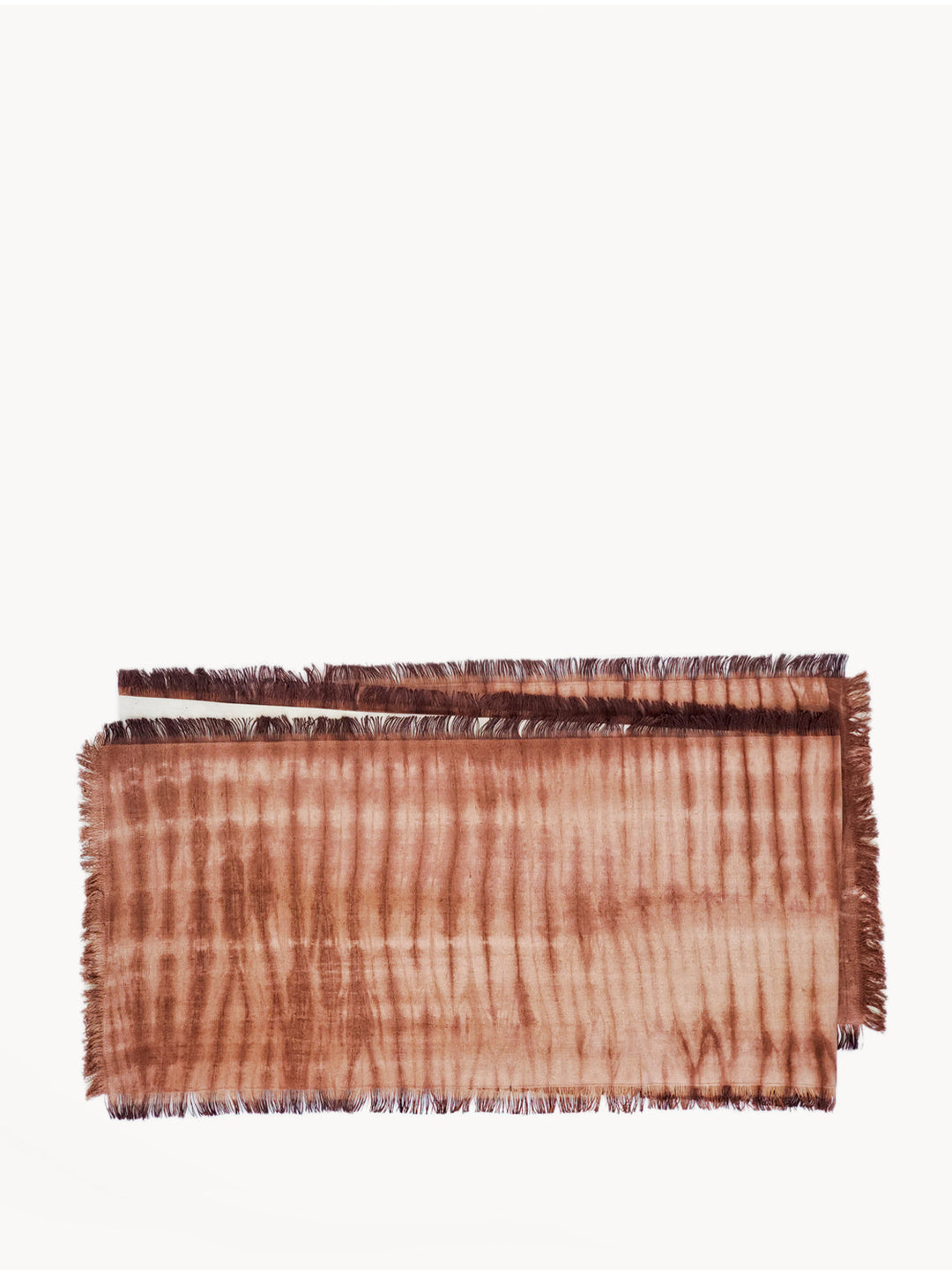 Fringed shibori-dyed cotton table runner in warm rust and cream tones