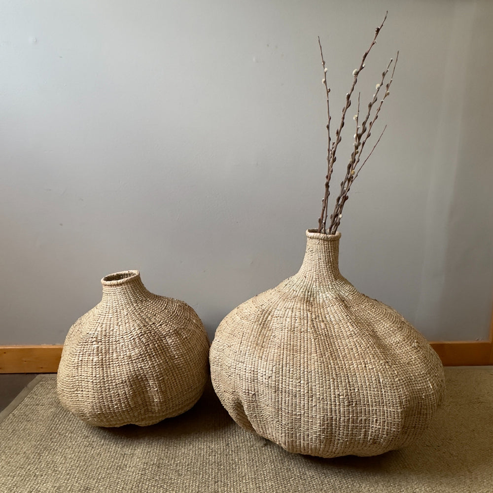 Two handwoven Garlic Tonga baskets on the floor, the larger filled with dried branches, wild Ilala palm from Zimbabwe.