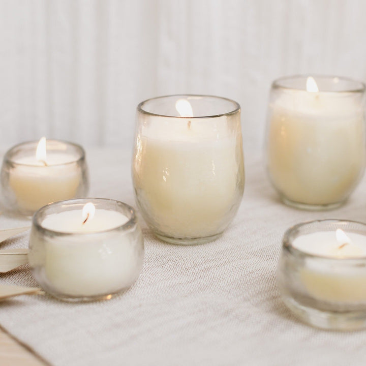 Three unscented soy votive candles glowing in hammered-glass holders.