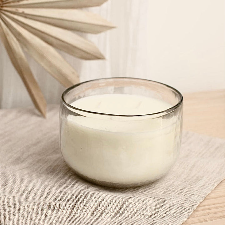 Triple-wick soy wax candle in a textured hand-blown glass bowl with a warm glow.