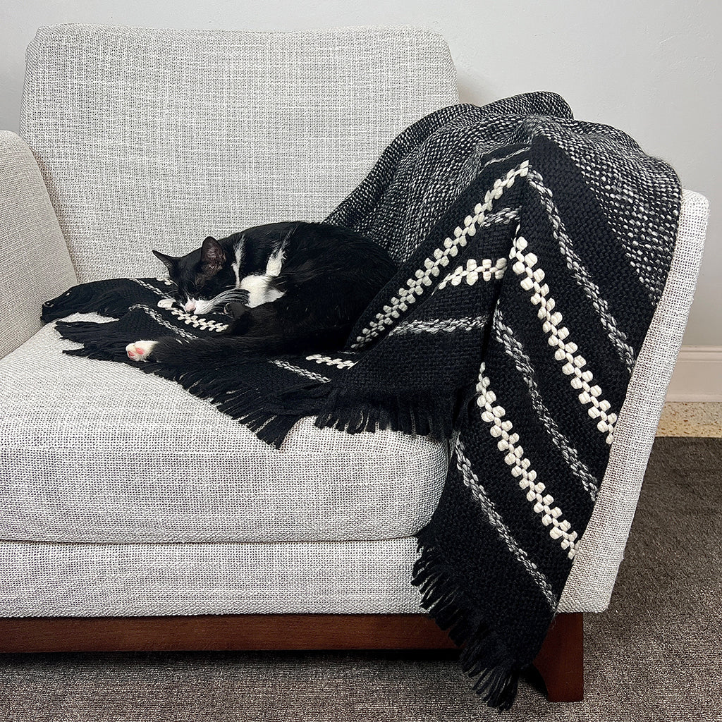 Black alpaca throw blanket with a heathered grey weave and cream stripes