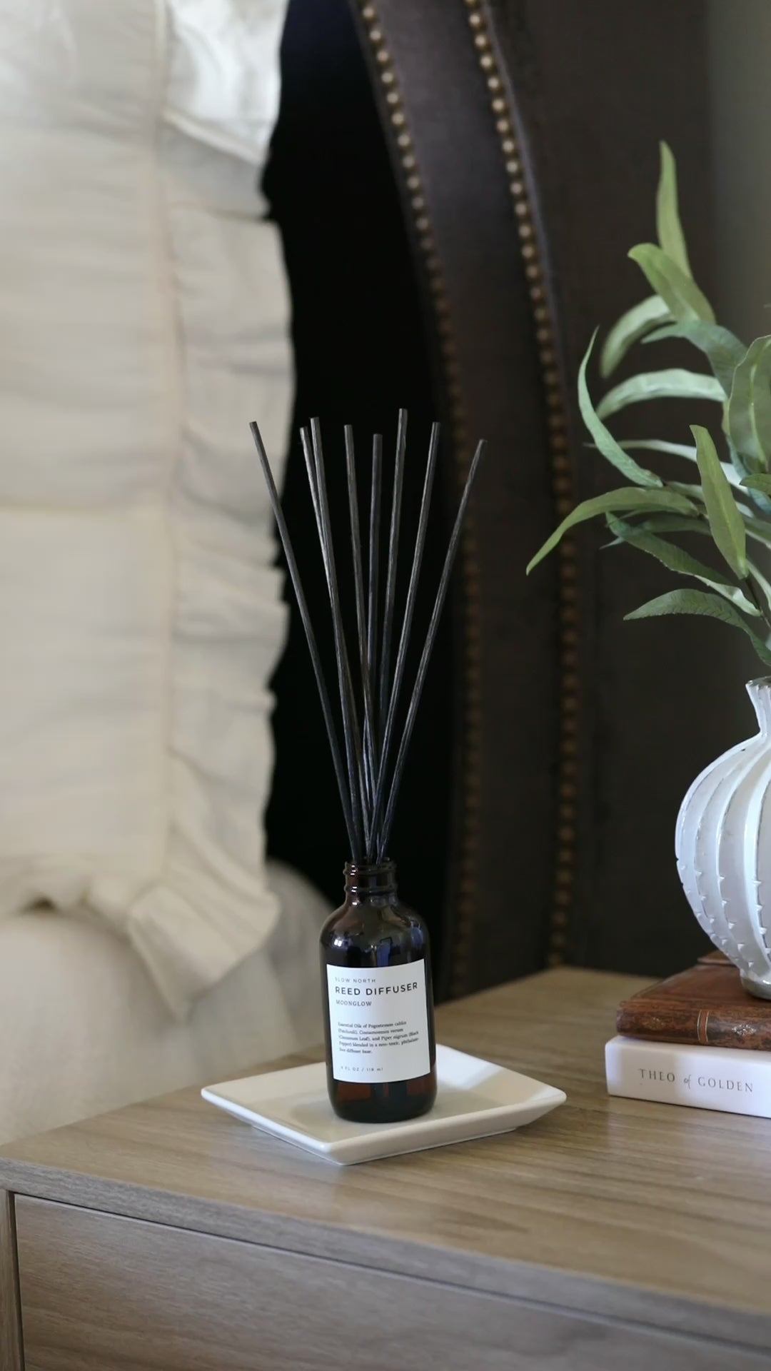 Reed diffuser bottle with warm aromatic blend and natural reed sticks.
