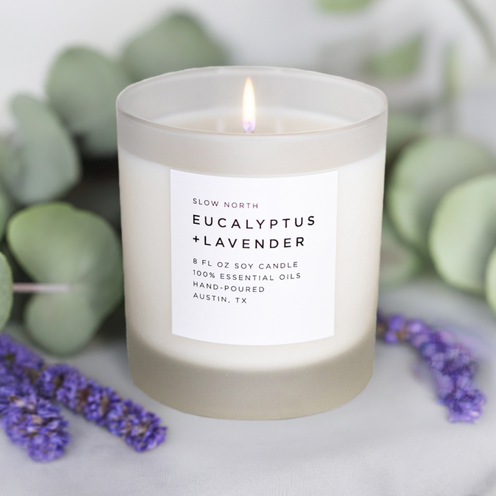 Eucalyptus lavender candle with lit wick in a glass jar.