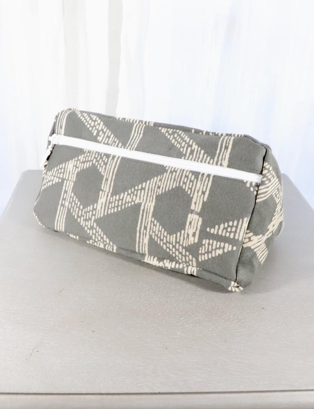 Grey cotton toiletry bag with a triangle or floral pattern.