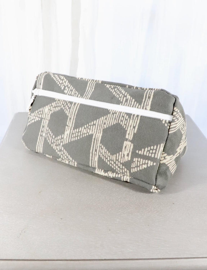 Grey cotton toiletry bag with a triangle or floral pattern.