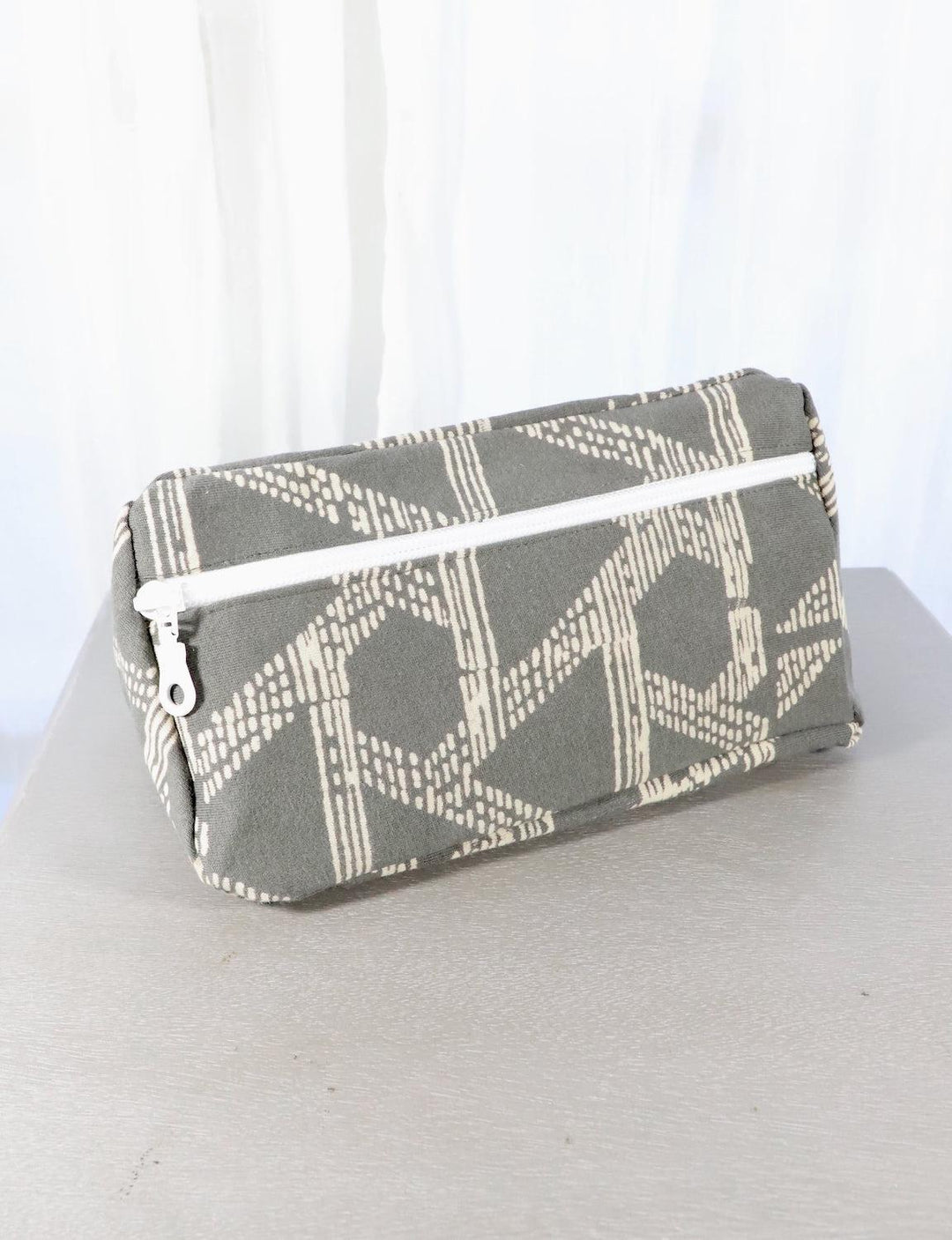 Grey cotton toiletry bag with a triangle or floral pattern.