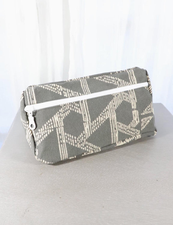 Grey cotton toiletry bag with a triangle or floral pattern.