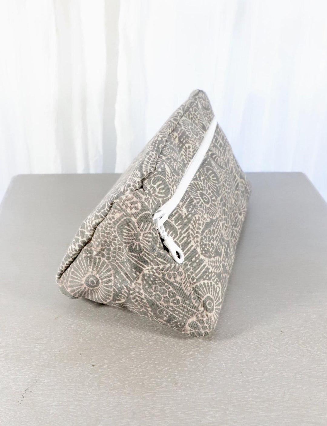 Grey cotton toiletry bag with a zippered opening, compact design.