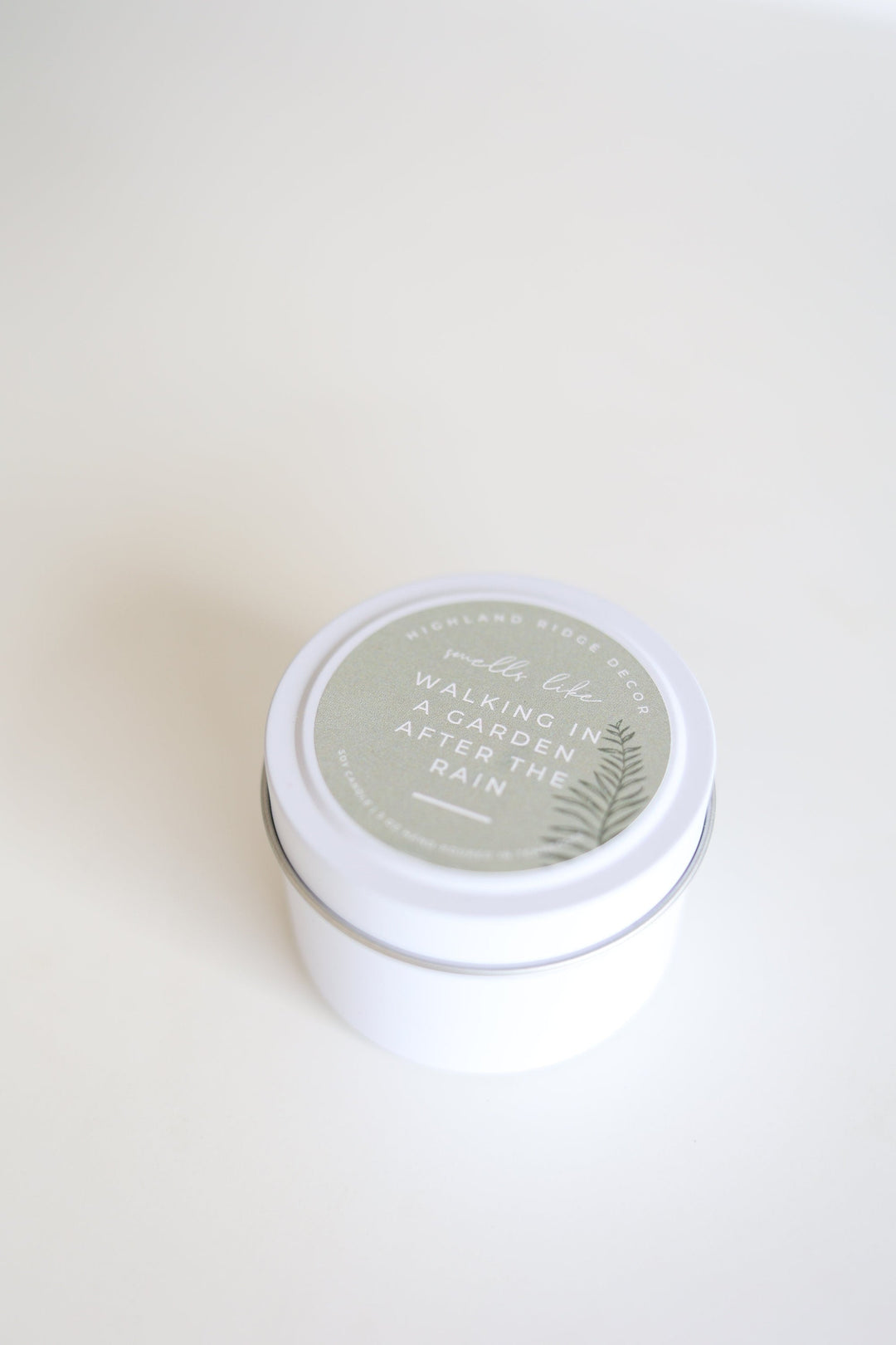 Hand-poured soy Garden Rain candle in a tin with a wooden wick.