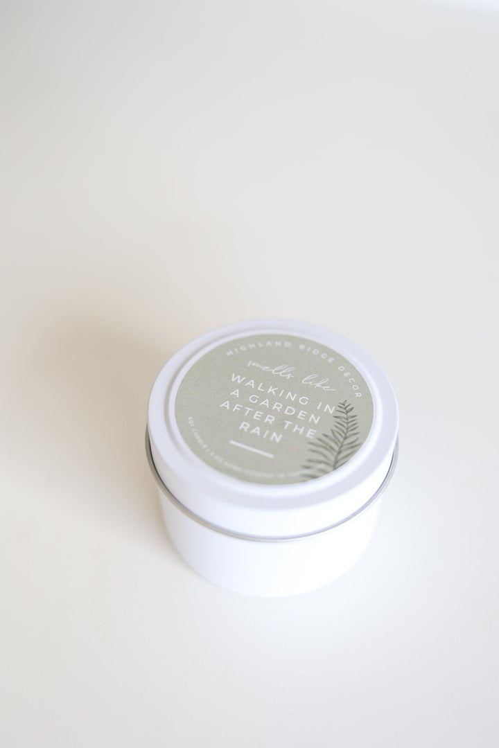 Hand-poured soy Garden Rain candle in a tin with a wooden wick.