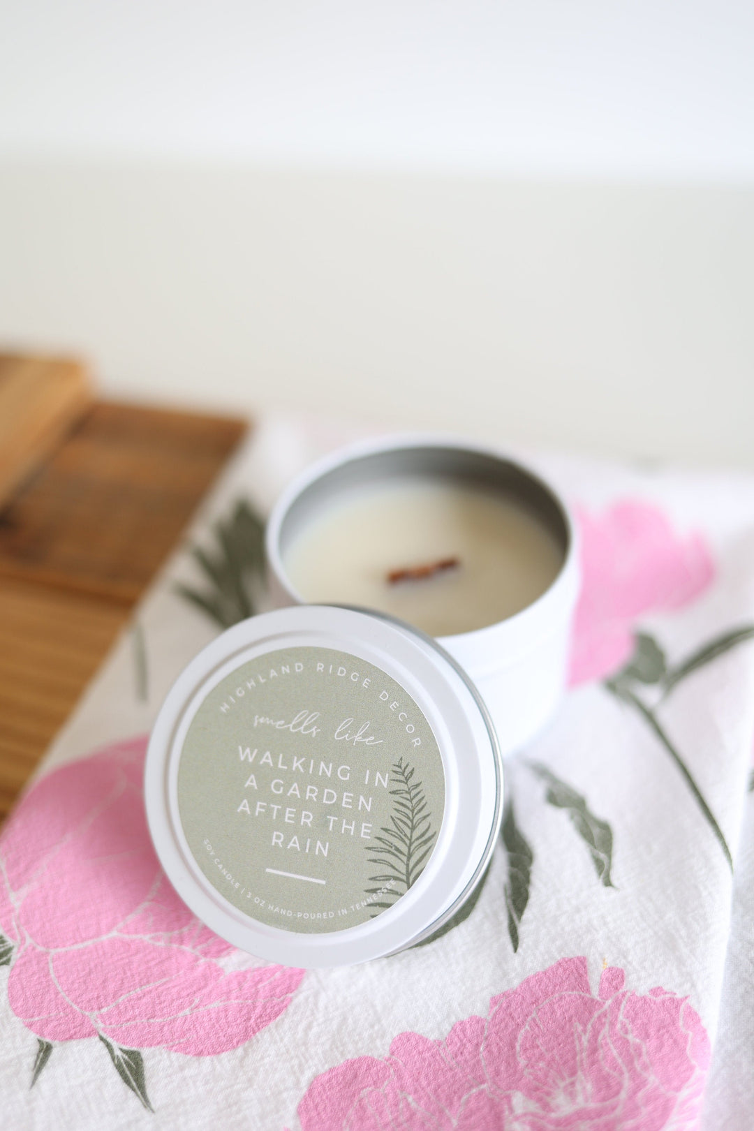 Hand-poured soy Garden Rain candle in a tin, wooden wick inside.