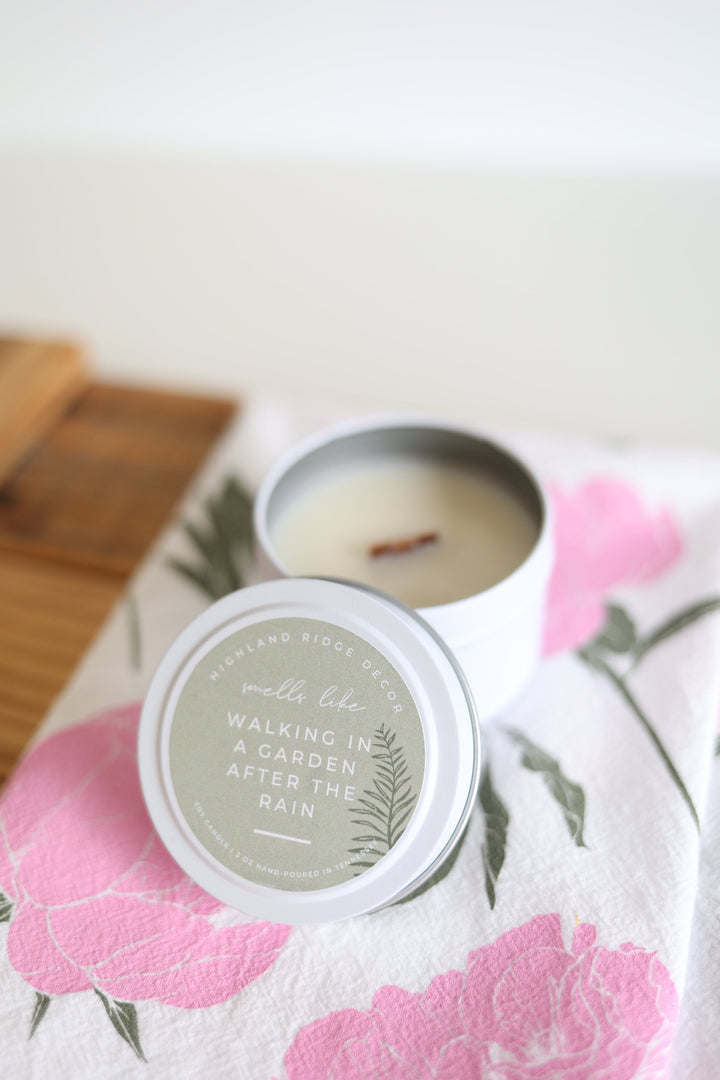 Hand-poured soy Garden Rain candle in a tin, wooden wick inside.