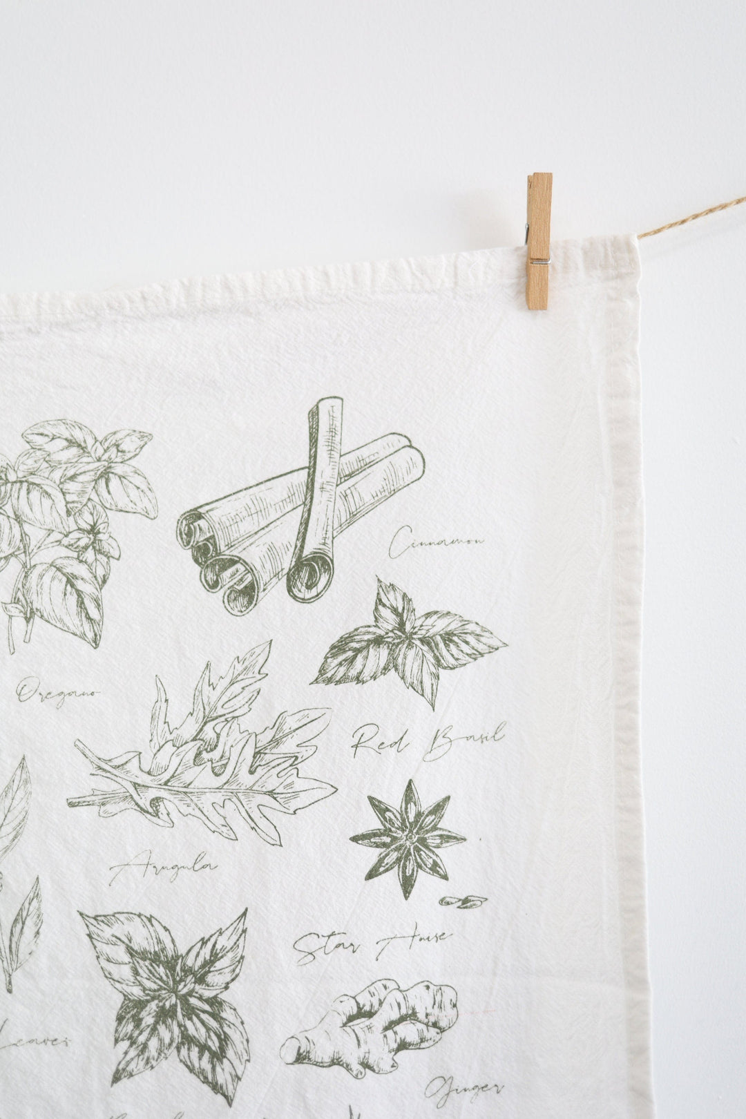 Cotton tea towel with watercolor green herb illustrations.