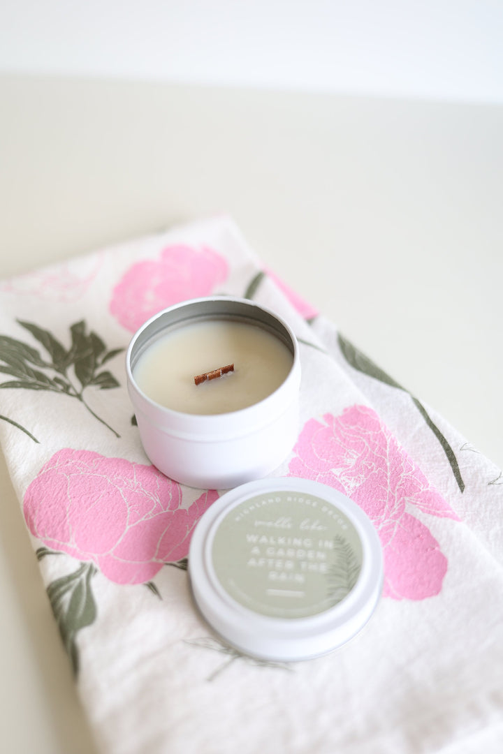 Garden Rain soy candle in a tin with a floral and greenery label.