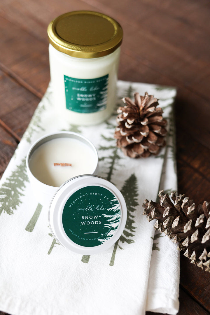 Snowy Woods soy candle tin with a winter forest scene on the label.