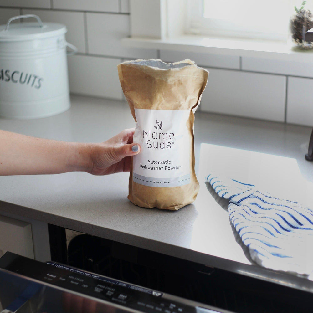 Natural, PVA-free dishwasher powder in a resealable bag with a scoop.
