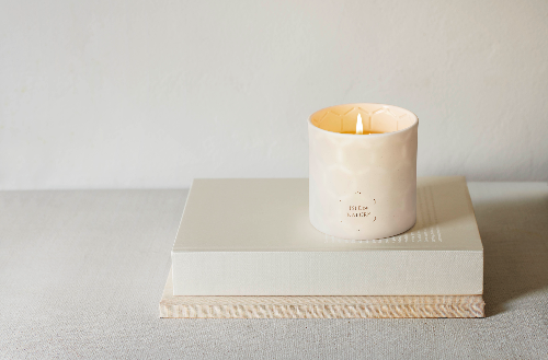 Beeswax candle in a natural beige clay vessel with a simple, elegant design.