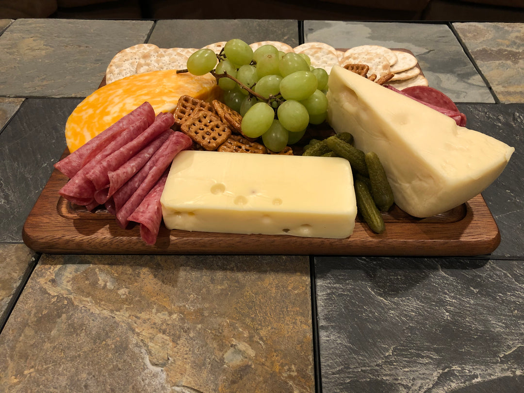 Acacia cheeseboard and matching wood knife on a neutral background.