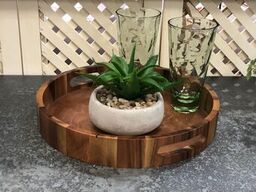 Round acacia wood serving tray with side handles and natural grain.