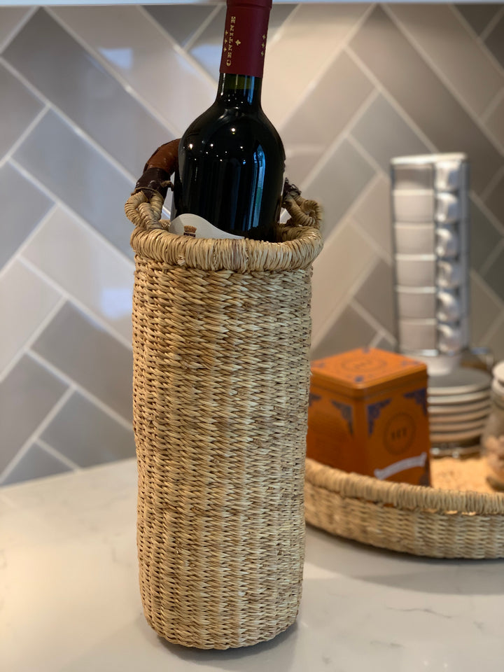Handwoven straw Astoria vase and wine holder with a leather handle, a decorative natural-fiber piece.