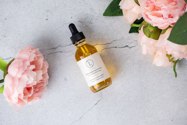 Grapefruit body oil in a clear bottle with a golden cap.