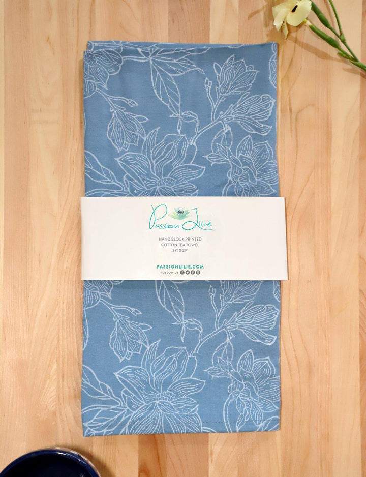 Magnolia cotton tea towel, hand block printed with a floral design on soft blue.