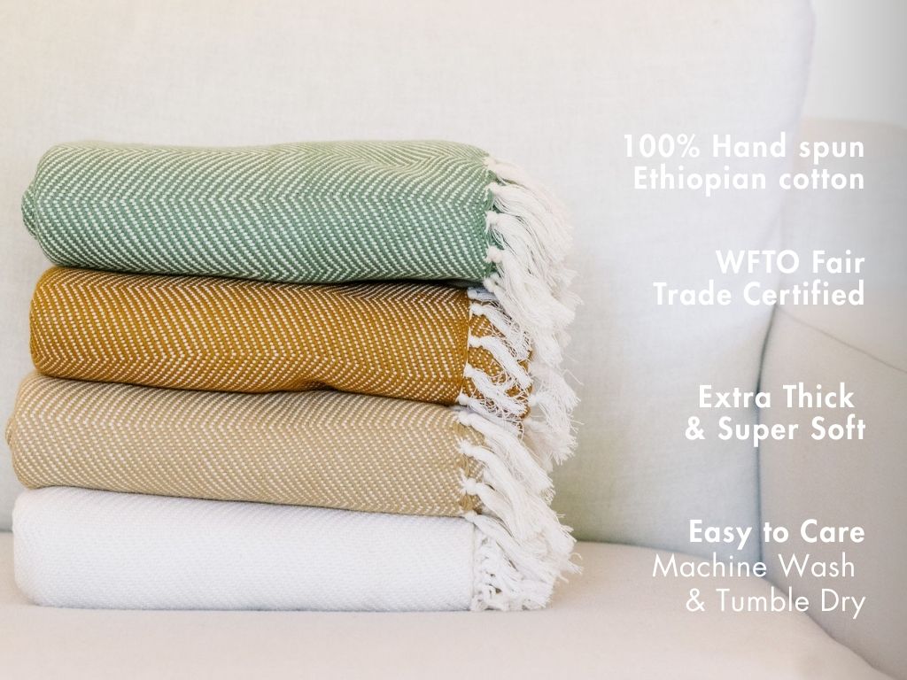 Stack of folded herringbone cotton throws with notes: 100% hand-spun Ethiopian cotton, WFTO Fair Trade certified, extra thick and soft, machine wash and tumble dry.