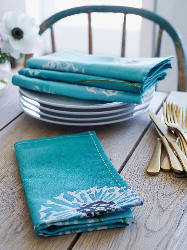 Aqua linen-cotton napkin set with a dandelion print, shown folded.