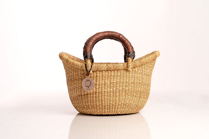 The Petite Victoria handwoven straw basket bag with a leather handle.