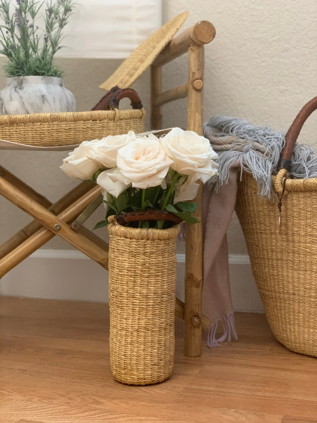 Decorative handwoven straw vase and wine holder with a leather handle and natural woven texture.