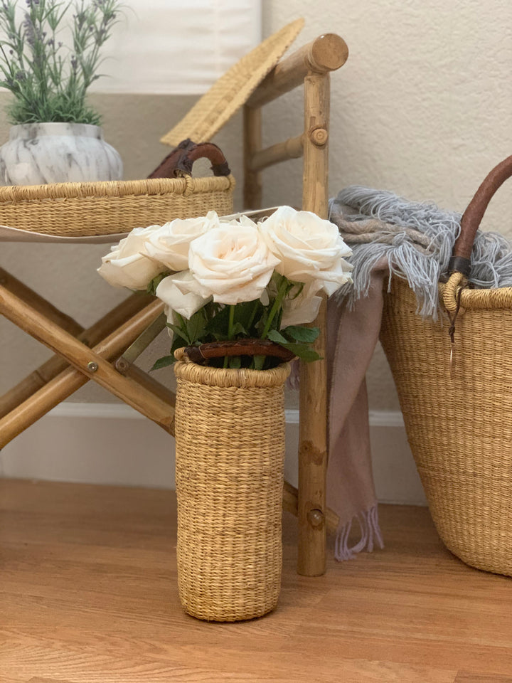 Decorative handwoven straw vase and wine holder with a leather handle and natural woven texture.