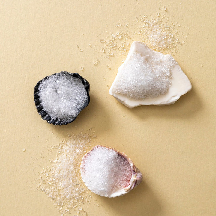 Bath salts in a clear glass jar with textured coarse salt crystals.
