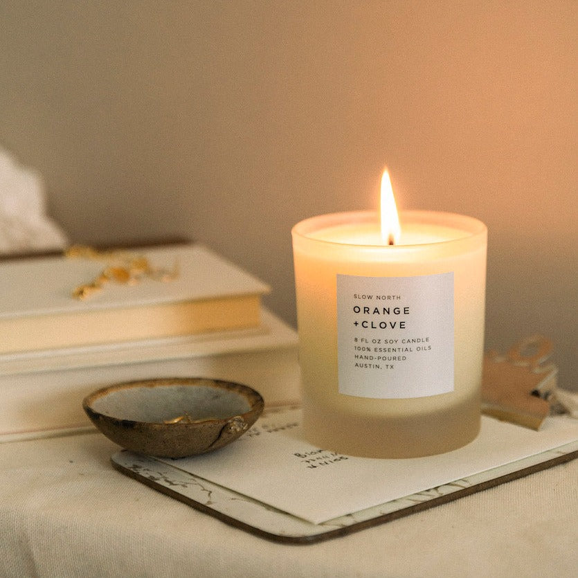 Orange clove soy candle on a nightstand with warm scent profile.
