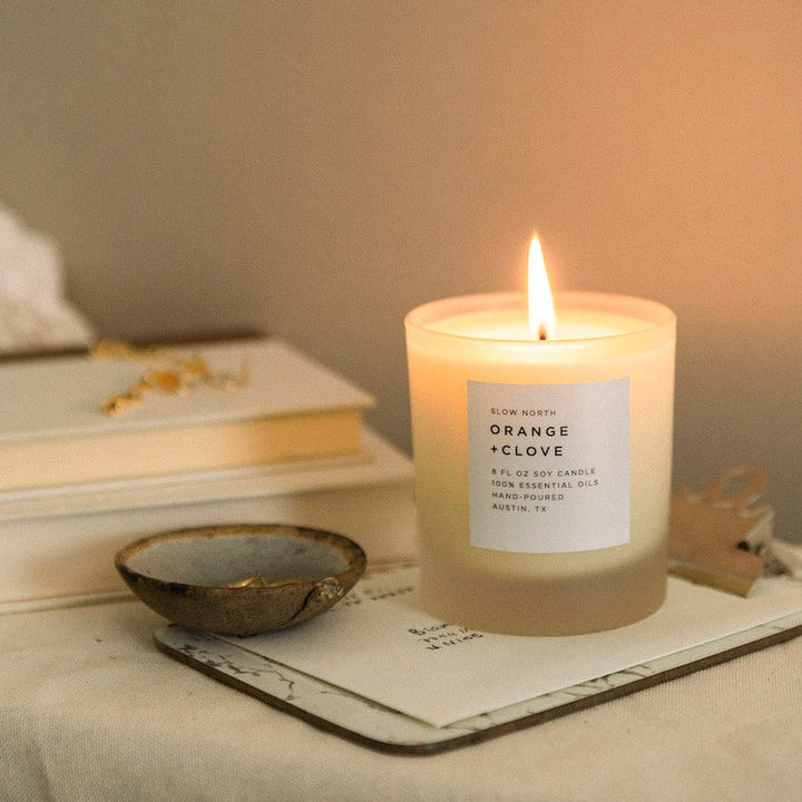 Orange clove soy candle on a nightstand with warm scent profile.