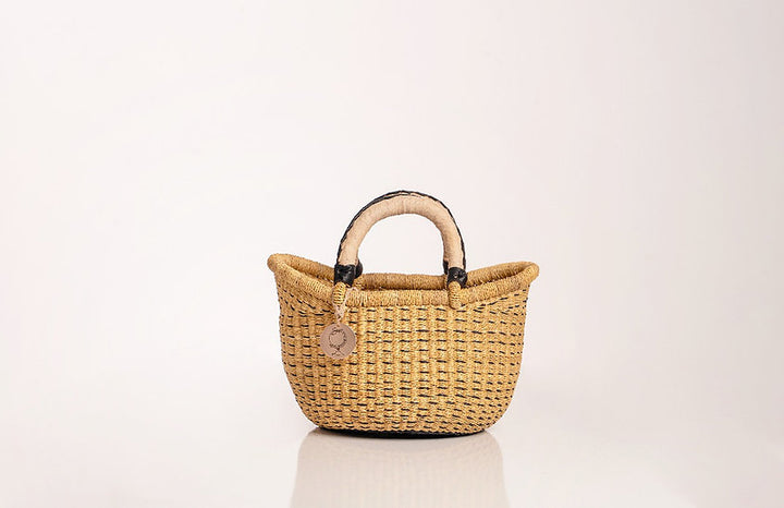 The Petite Victoria handwoven straw basket bag, showing its craftsmanship and natural materials.