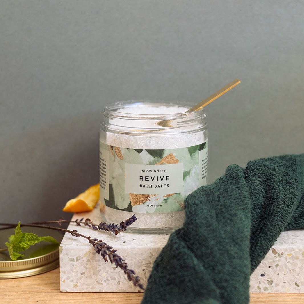 Colorful mineral bath salts in a glass jar with branded label.