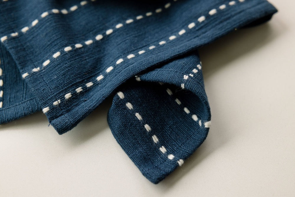 Close-up of a navy cocktail napkin showing the woven line pattern