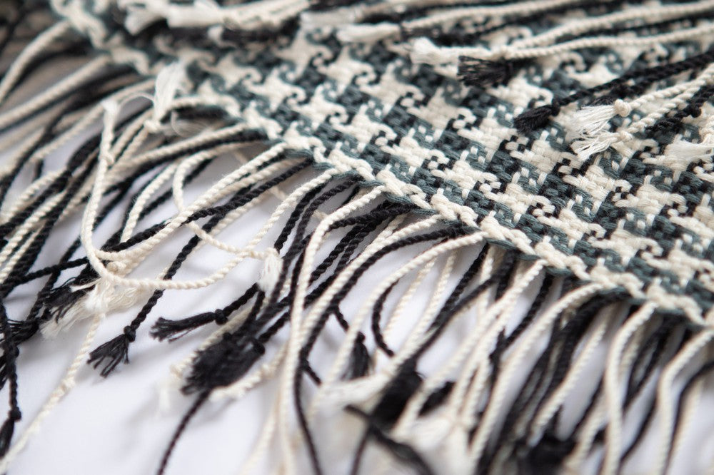 Hand-tied fringe at the end of a slate and white pinwheel cotton throw.