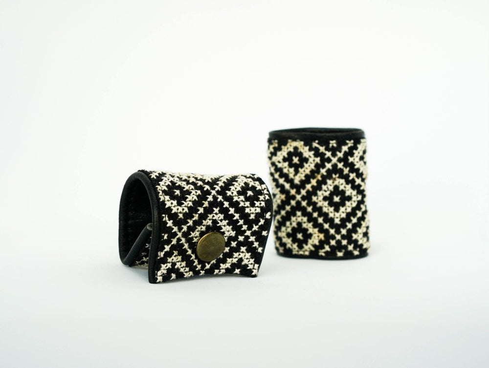 Hand-embroidered black-and-white tatreez napkin rings with a leather snap closure.