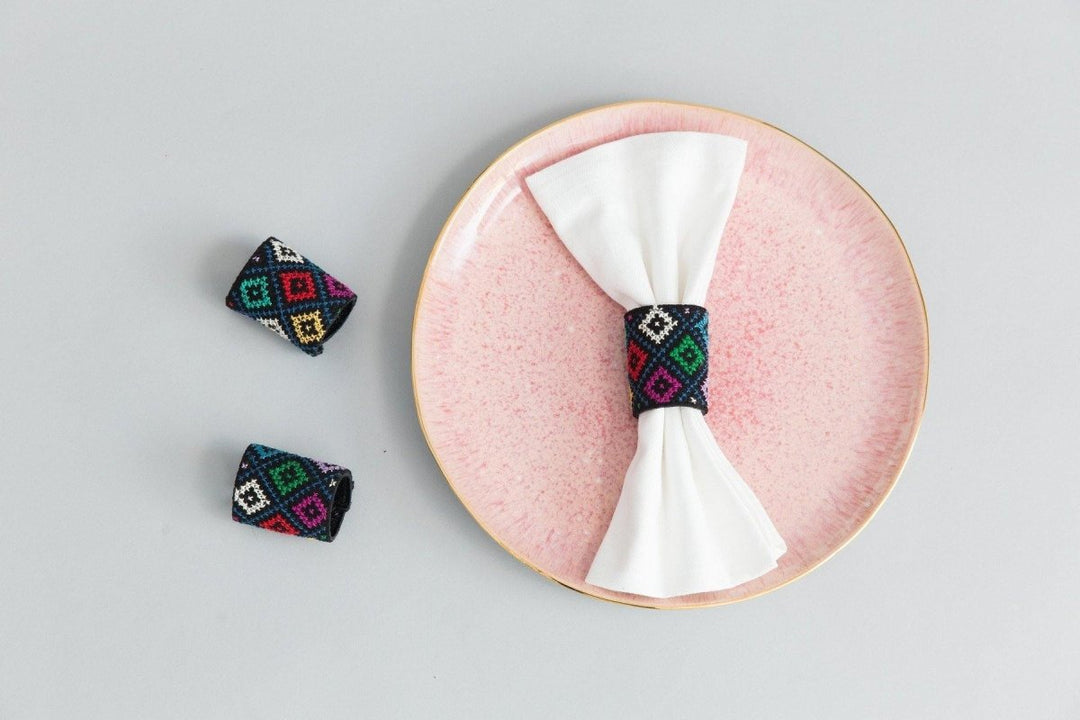 Set of two black napkin rings with multicolor diamond tatreez cross-stitch.
