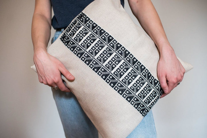Hand-embroidered cushion cover, black-and-ivory Carnation cross-stitch on natural cotton.