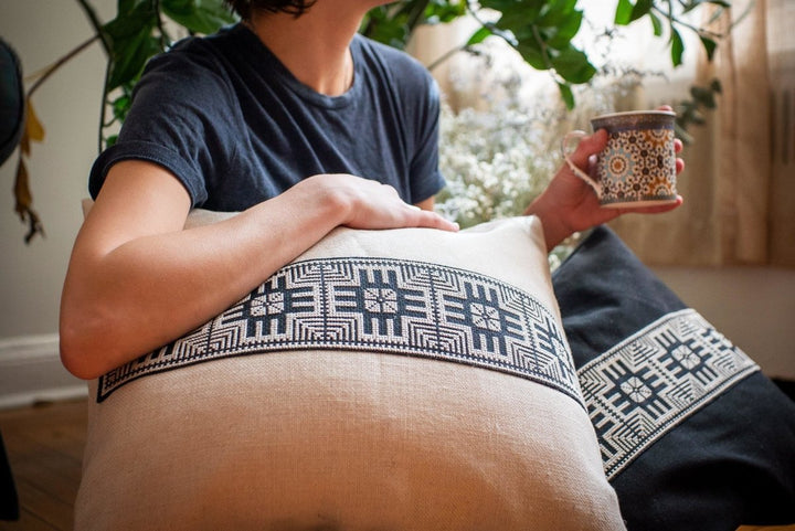 Hand-embroidered cushion cover, black-and-ivory Moon with Feathers cross-stitch on natural cotton.